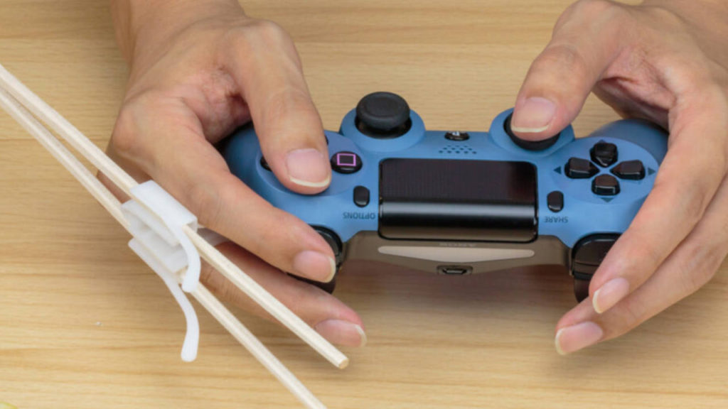 Akcesoria dla graczy - japanese gaming chopsticks - gracz gra na DualShock 4 i ma w ręce gamingowe pałeczki