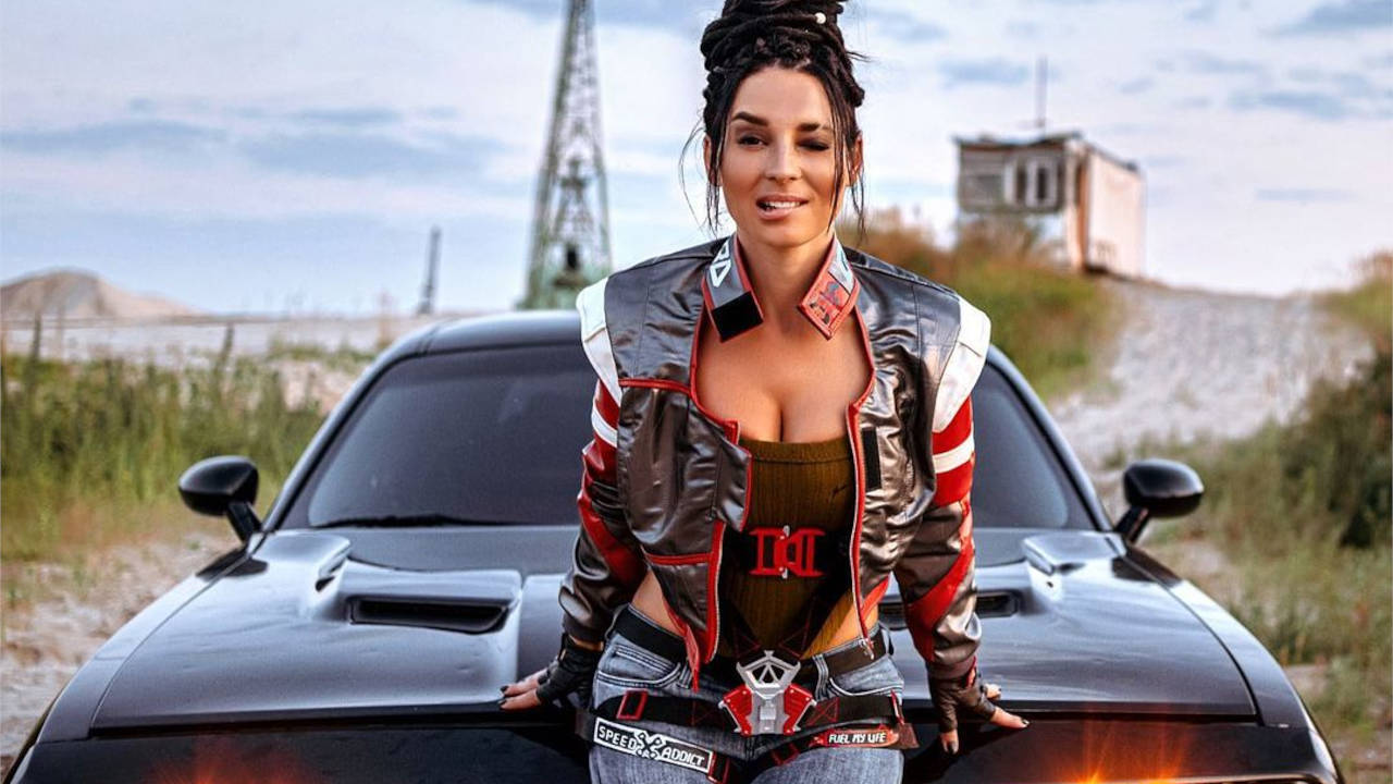 Cyberpunk 2077 - Anna Shakh jako Panam Palmer opiera się o auto i zmysłowo przygryza wargę