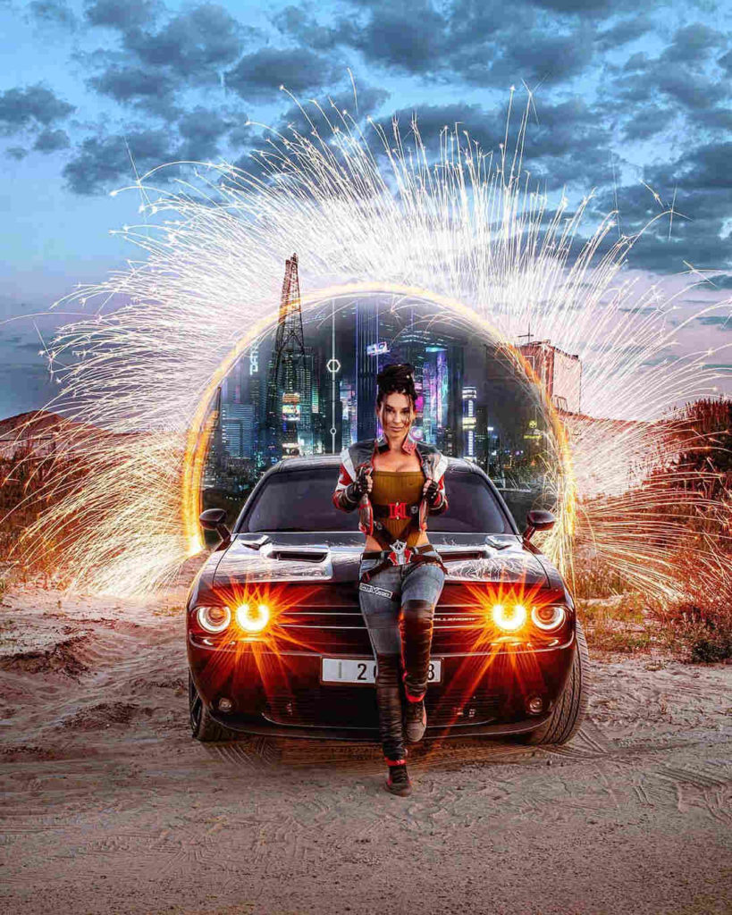 Cyberpunk 2077 - Anna Shakh jako Panam Palmer opiera się o auto na tle portalu do świata Cyberpunka, w tle Night City