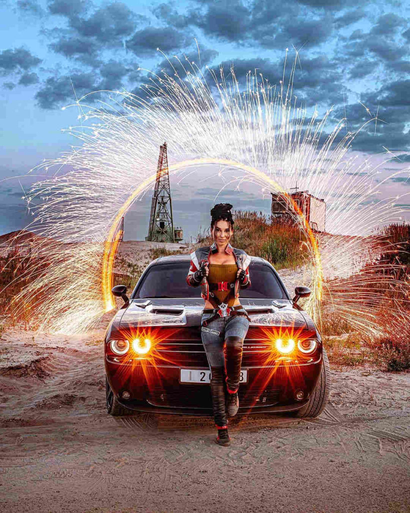 Cyberpunk 2077 - Anna Shakh jako Panam Palmer opiera się o auto na tle portalu do świata Cyberpunka