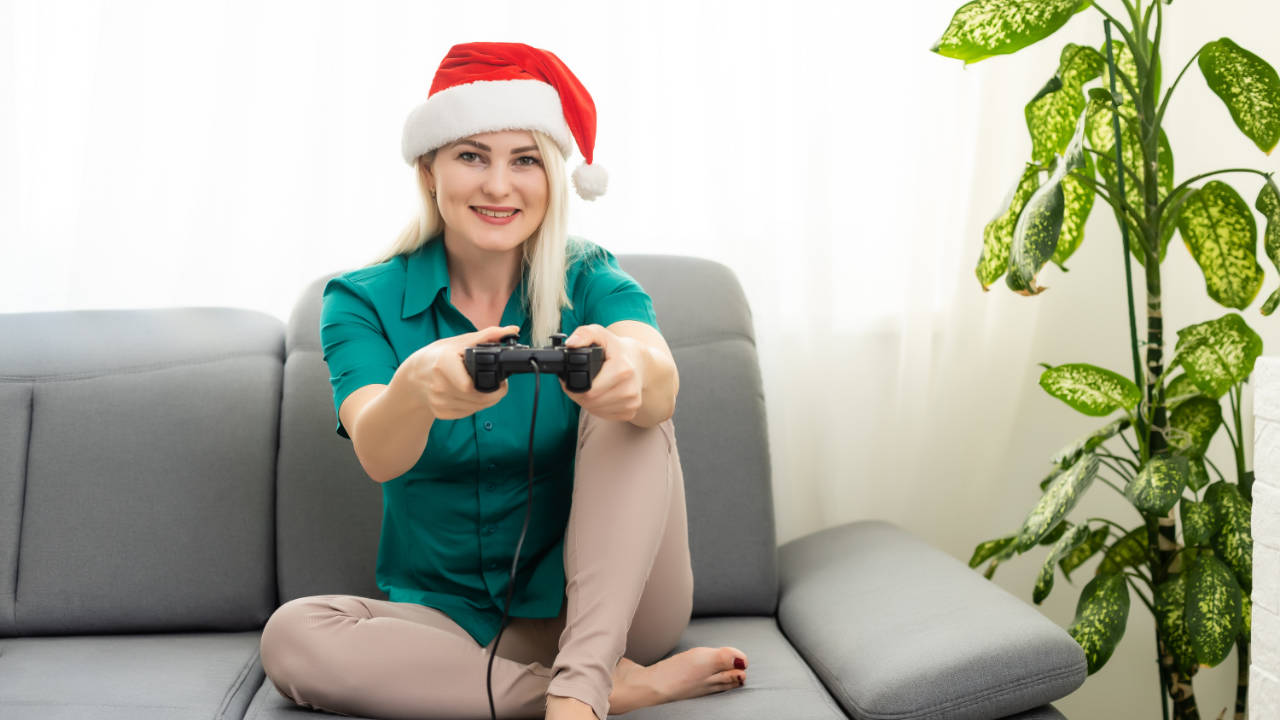 prezent dla gracza - pani w czapce Mikołaja gra na konsoli