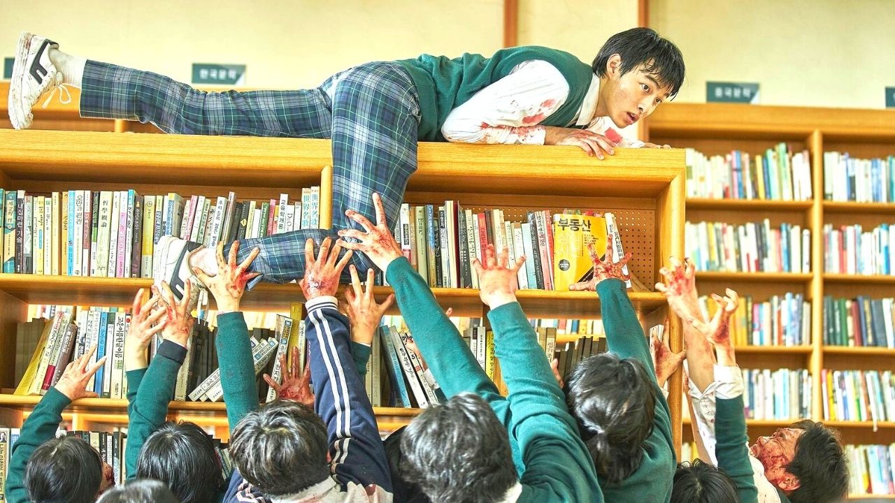 chłopak ukrywa się przed grupą zombie na szczycie regałów w bibliotece