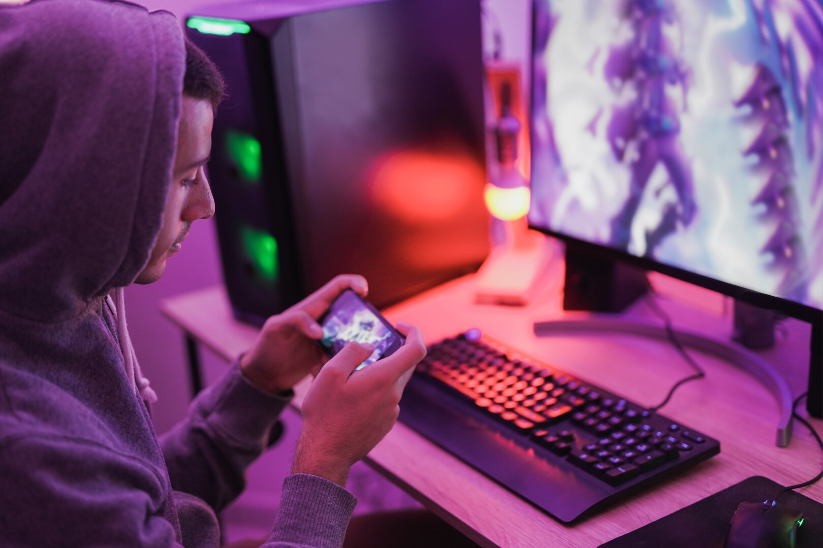 Young boy play video games at home using computer and mobile phone